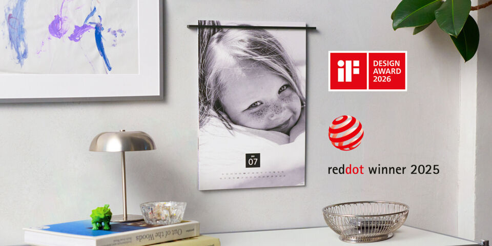 Ein schöner Kalender hängt an der Wand. Darauf ist ein lächelndes Kind mit Sommersprossen zu sehen. Das Bild lässt Freude und Lebensfreude a